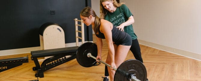 physical therapist cuing for proper form on barbell deadlift