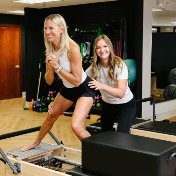 physical therapist correcting hip form on lateral lunge on Pilates reformer