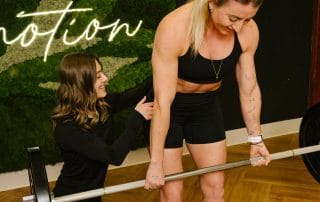 physical therapist correcting form on barbell deadlift