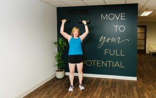 woman performing overhead press with dumb bells
