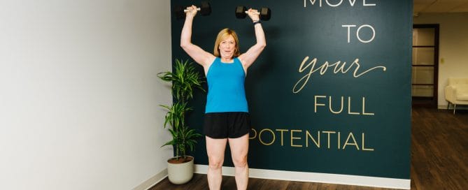 woman performing overhead press with dumb bells