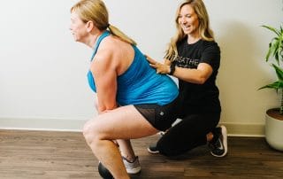physical therapist assisting women with deadlift form